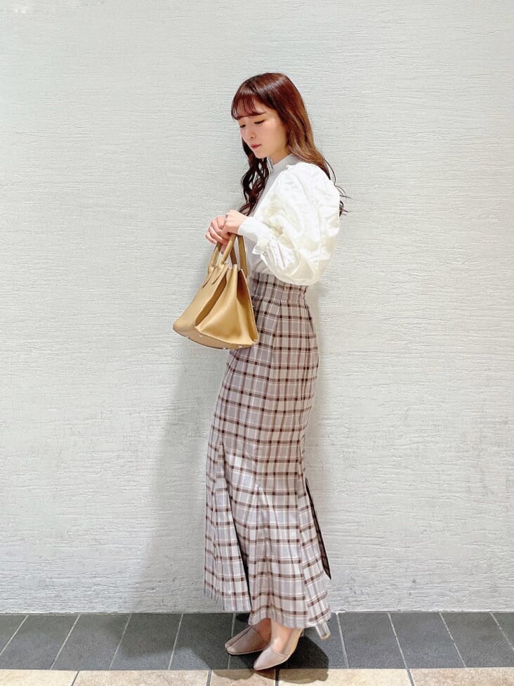 ベージュ系のブーツ、グレー系のスカート、ホワイト系のニット/セーターを着用したレディースの冬コーディネートの2枚目の写真