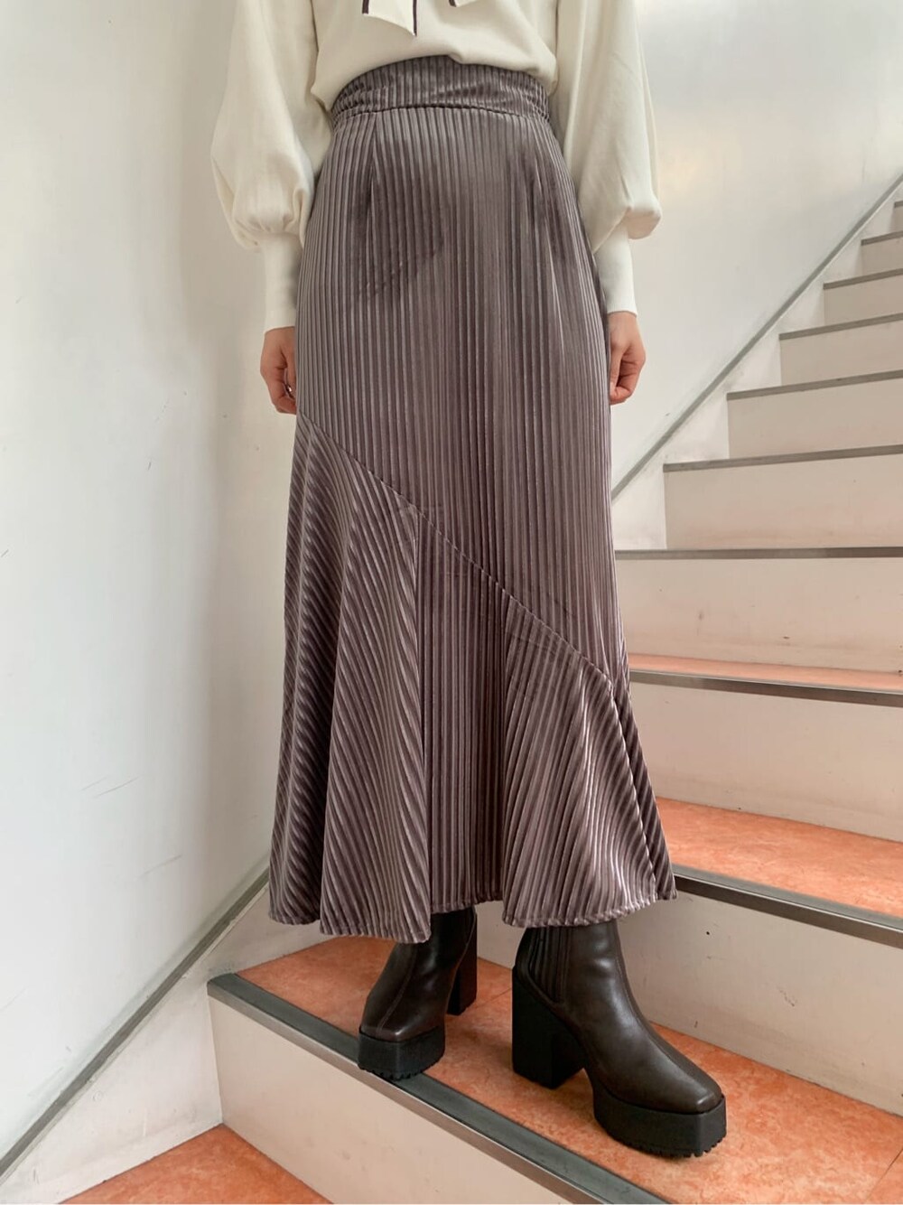 ホワイト系のニット/セーター、ブラウン系のブーツ、ベージュ系のスカートを着用したレディースの秋コーディネートの6枚目の写真