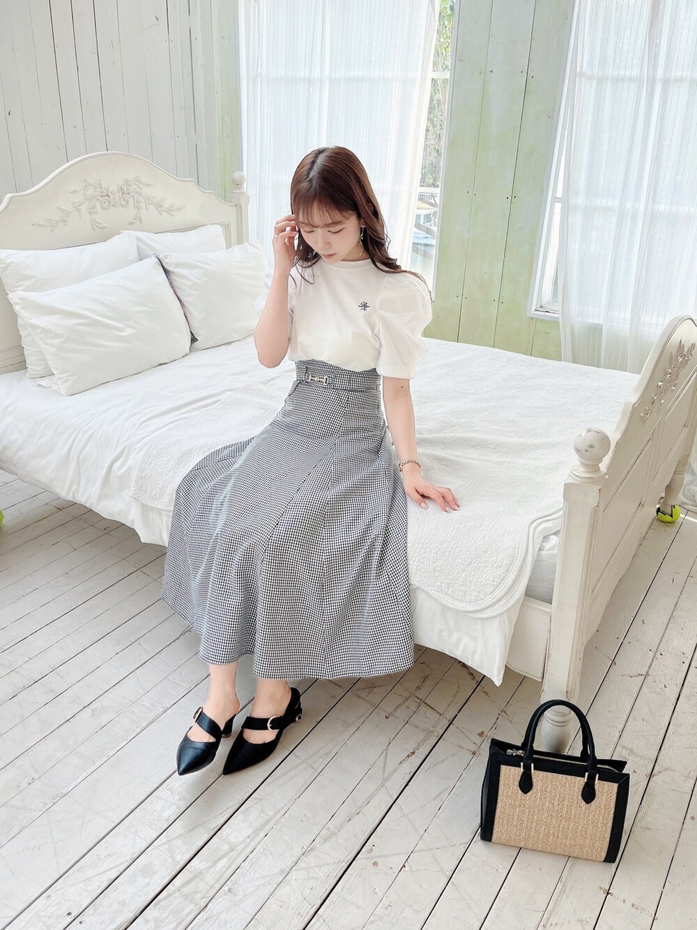 ホワイト系のTシャツ/カットソー、ブラック系のスカート、ブラック系のパンプスを着用したレディースの春コーディネートの2枚目の写真