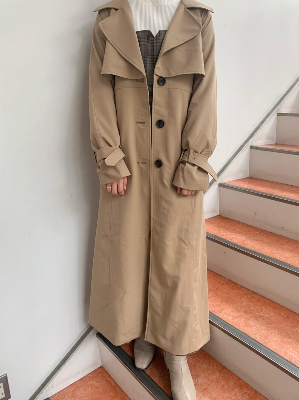 ベージュ系のトレンチコート、ベージュ系のブーツ、その他のジャンパースカートを着用したレディースの秋コーディネートの5枚目の写真