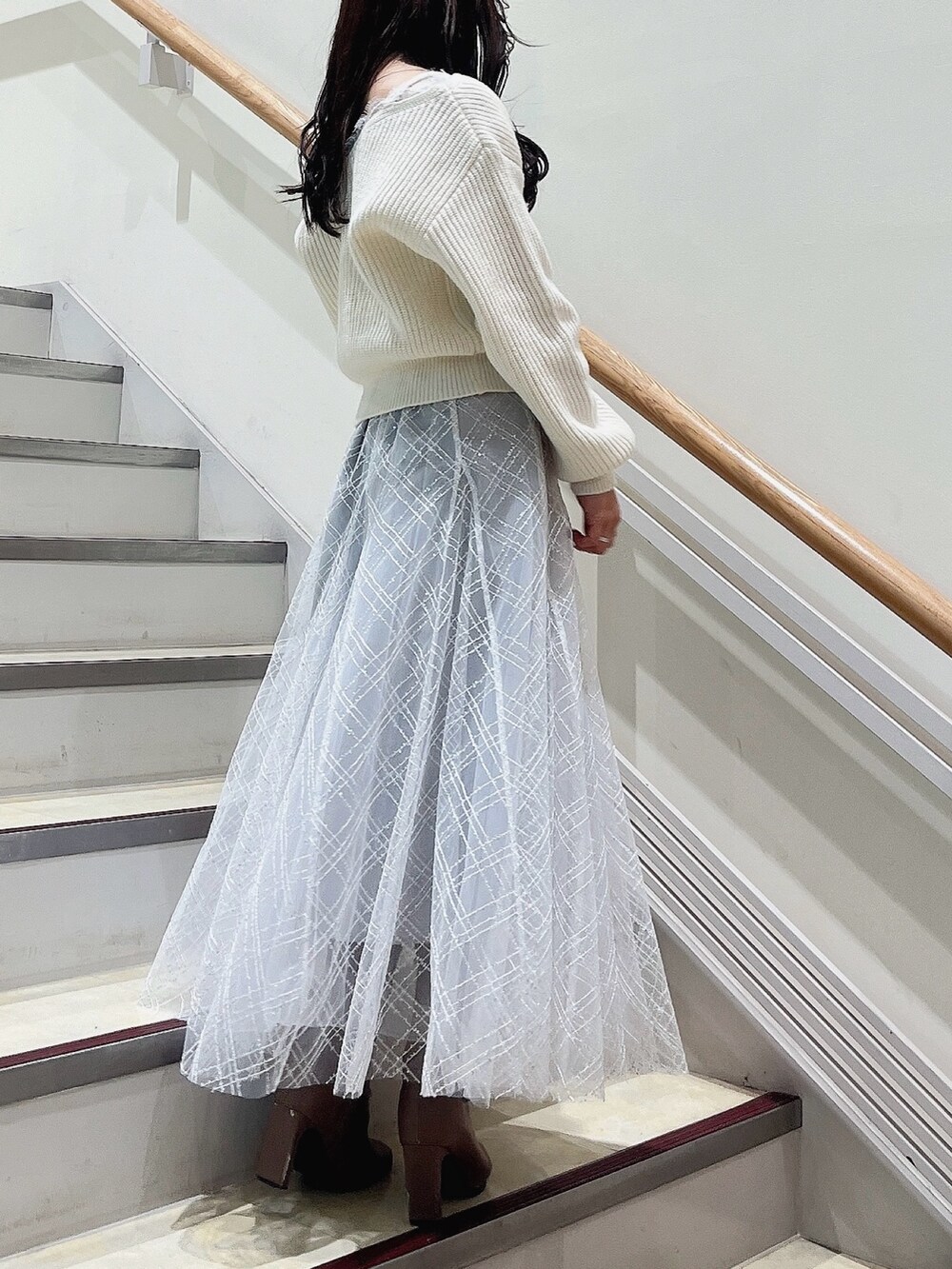 ホワイト系のニット/セーター、グレー系のスカート、ベージュ系のブーツを着用したレディースの冬コーディネートの4枚目の写真