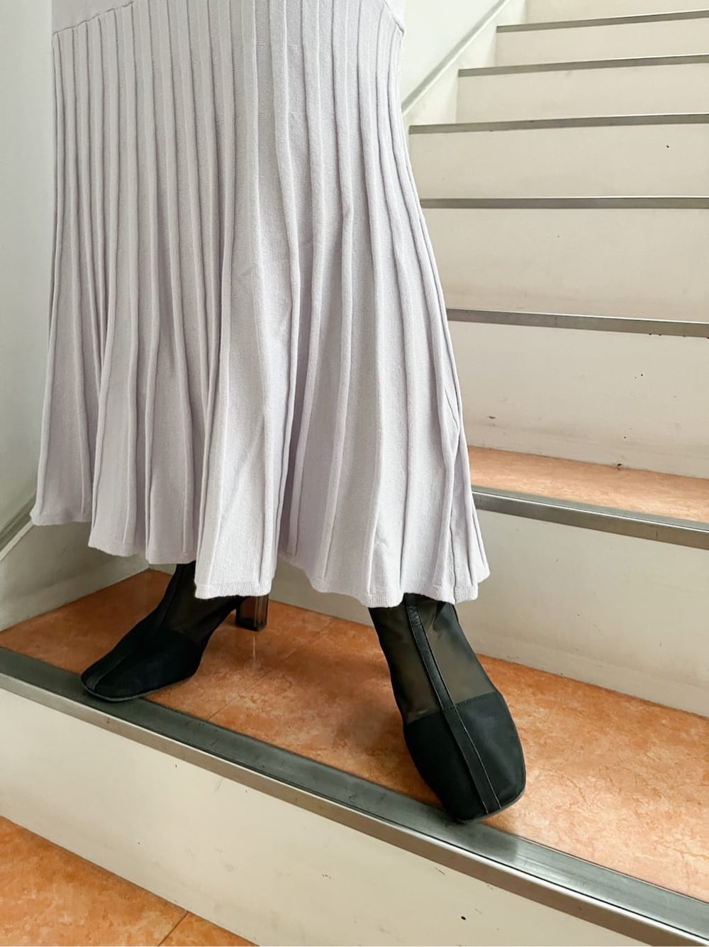 パープル系のワンピース、ブラック系のブーツ、ホワイト系のショルダーバッグを着用したレディースの冬コーディネートの9枚目の写真