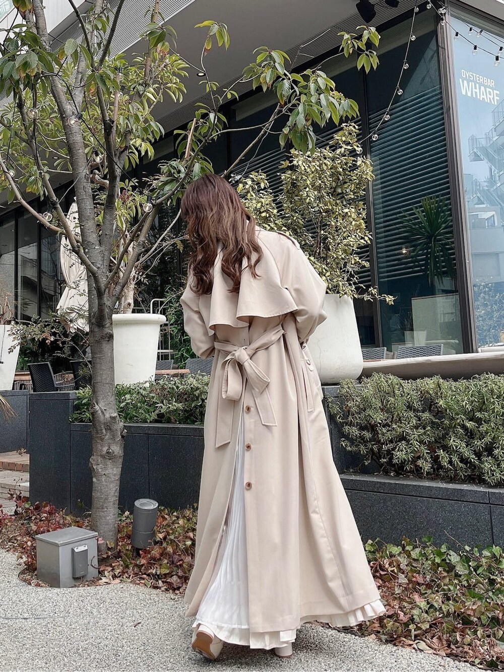ベージュ系のトレンチコート、ホワイト系のワンピース、ホワイト系のパンプスを着用したレディースの冬コーディネートの7枚目の写真