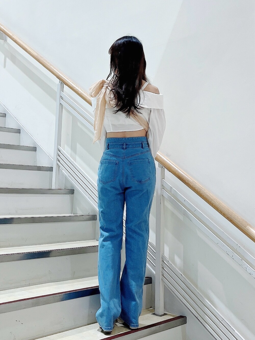 オレンジ系のベスト、ブルー系のデニムパンツ、ホワイト系のシャツ/ブラウスを着用したレディースの春コーディネートの6枚目の写真