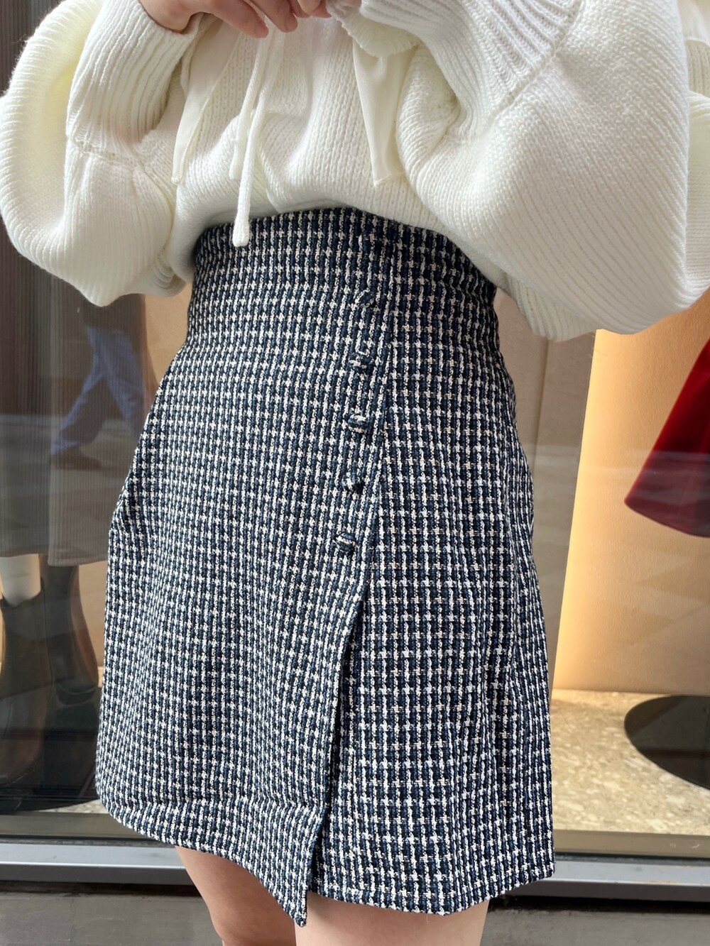 ホワイト系のニット/セーター、ブルー系のスカート、ブラック系のブーツを着用したレディースの秋コーディネートの8枚目の写真