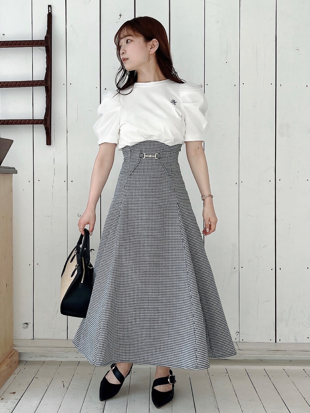 ホワイト系のTシャツ/カットソー、ブラック系のスカート、ブラック系のパンプスを着用したレディースの春コーディネートの6枚目の写真