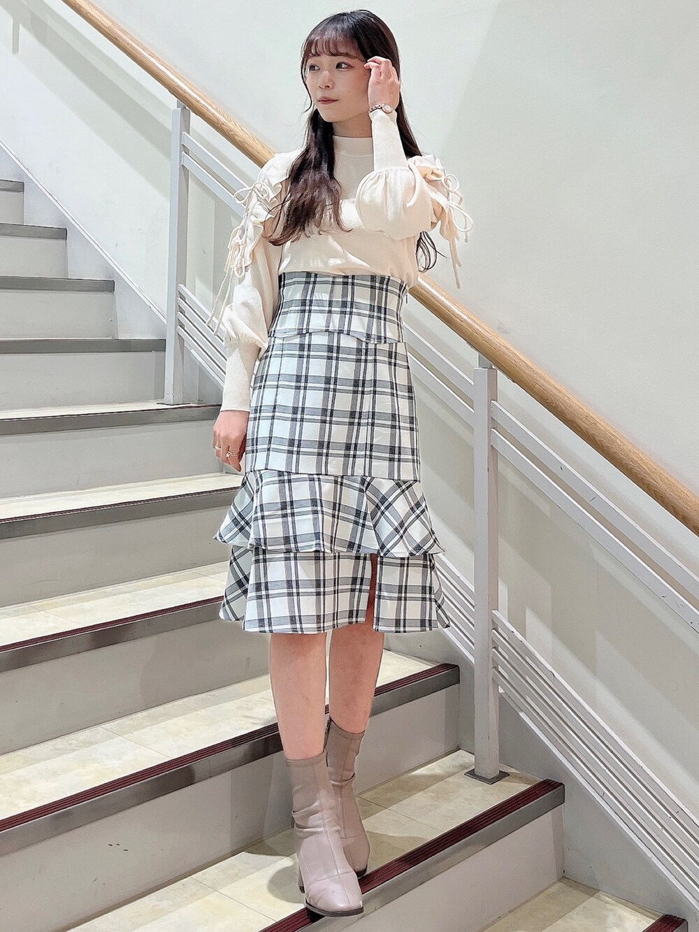 ホワイト系のニット/セーター、ホワイト系のスカート、ベージュ系のブーツを着用したレディースの冬コーディネートの2枚目の写真