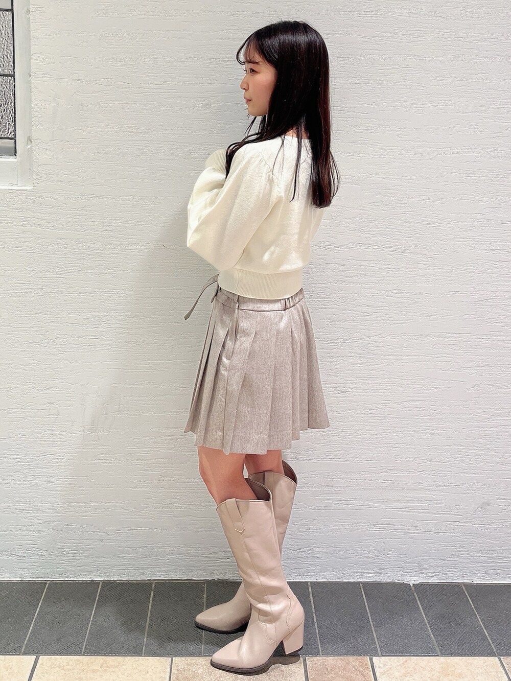 ホワイト系のニット/セーター、ベージュ系のスカート、ベージュ系のブーツを着用したレディースの冬コーディネートの3枚目の写真