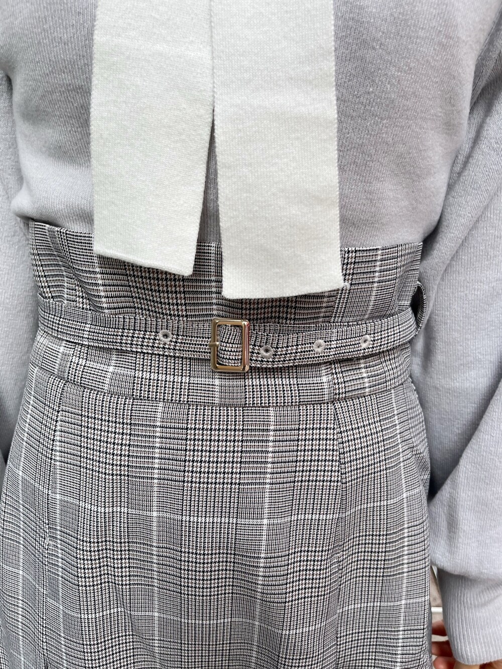 グレー系のニット/セーター、グレー系のスカート、ベージュ系のブーツを着用したレディースの冬コーディネートの10枚目の写真