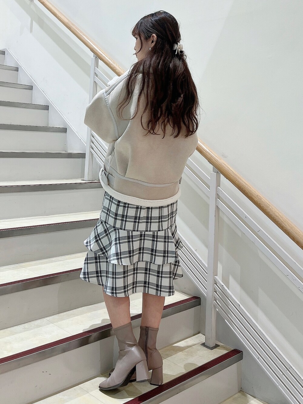 ホワイト系のブルゾン、ホワイト系のスカート、ベージュ系のブーツを着用したレディースの冬コーディネートの4枚目の写真