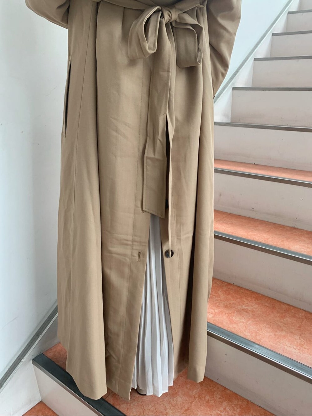 ベージュ系のトレンチコート、ベージュ系のブーツ、その他のジャンパースカートを着用したレディースの秋コーディネートの6枚目の写真