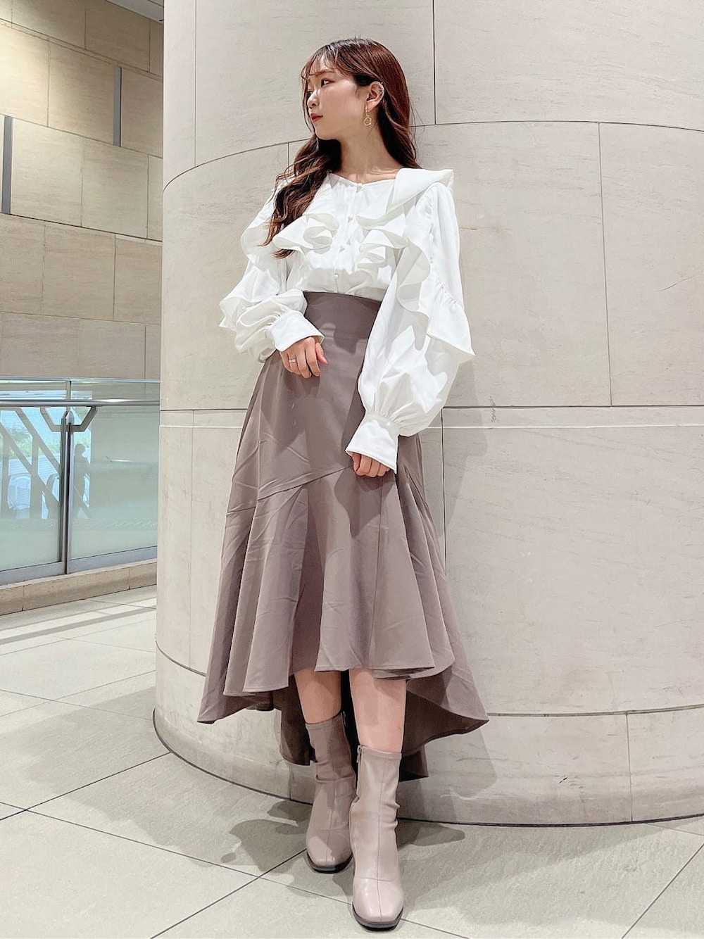 ベージュ系のブーツ、ベージュ系のスカート、ホワイト系のシャツ/ブラウスを着用したレディースの秋コーディネートの2枚目の写真