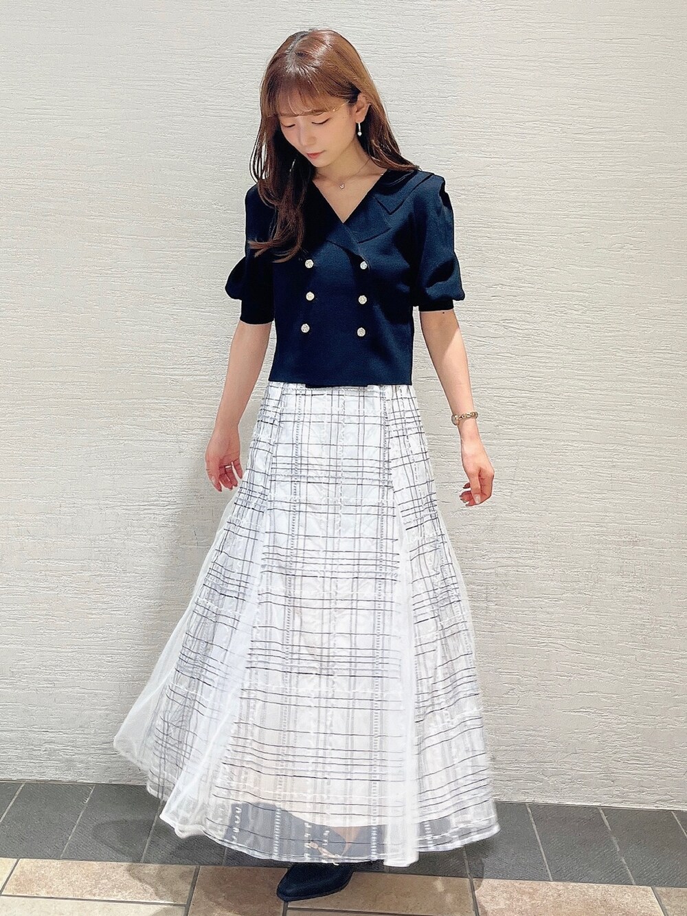 ブラック系のニット/セーター、ホワイト系のスカート、ブラック系のローファーを着用したレディースの夏コーディネートの3枚目の写真