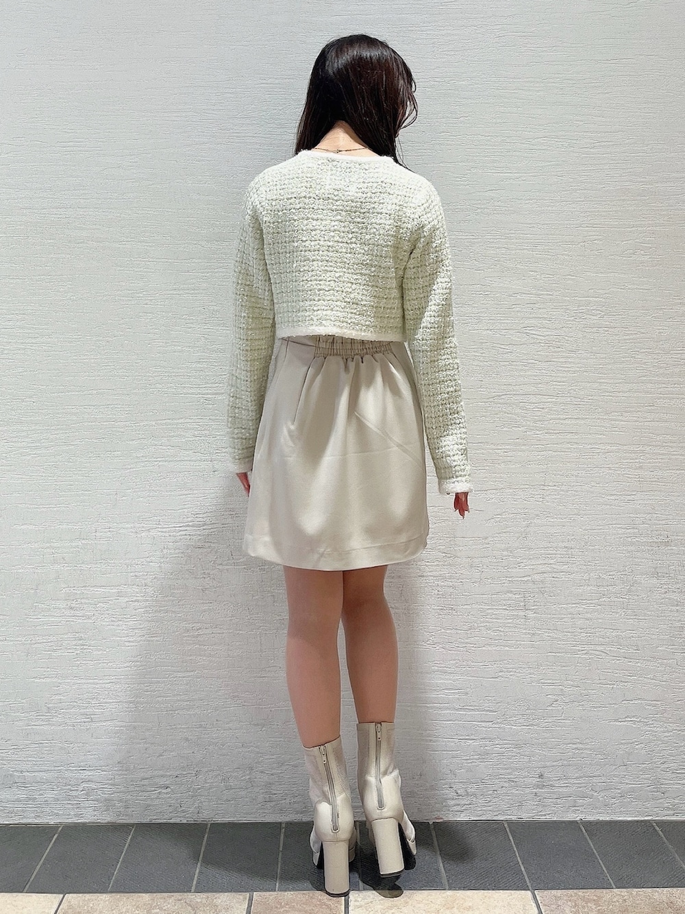 グリーン系のノーカラージャケット、ホワイト系のブーツ、ホワイト系のスカートを着用したレディースの冬コーディネートの3枚目の写真