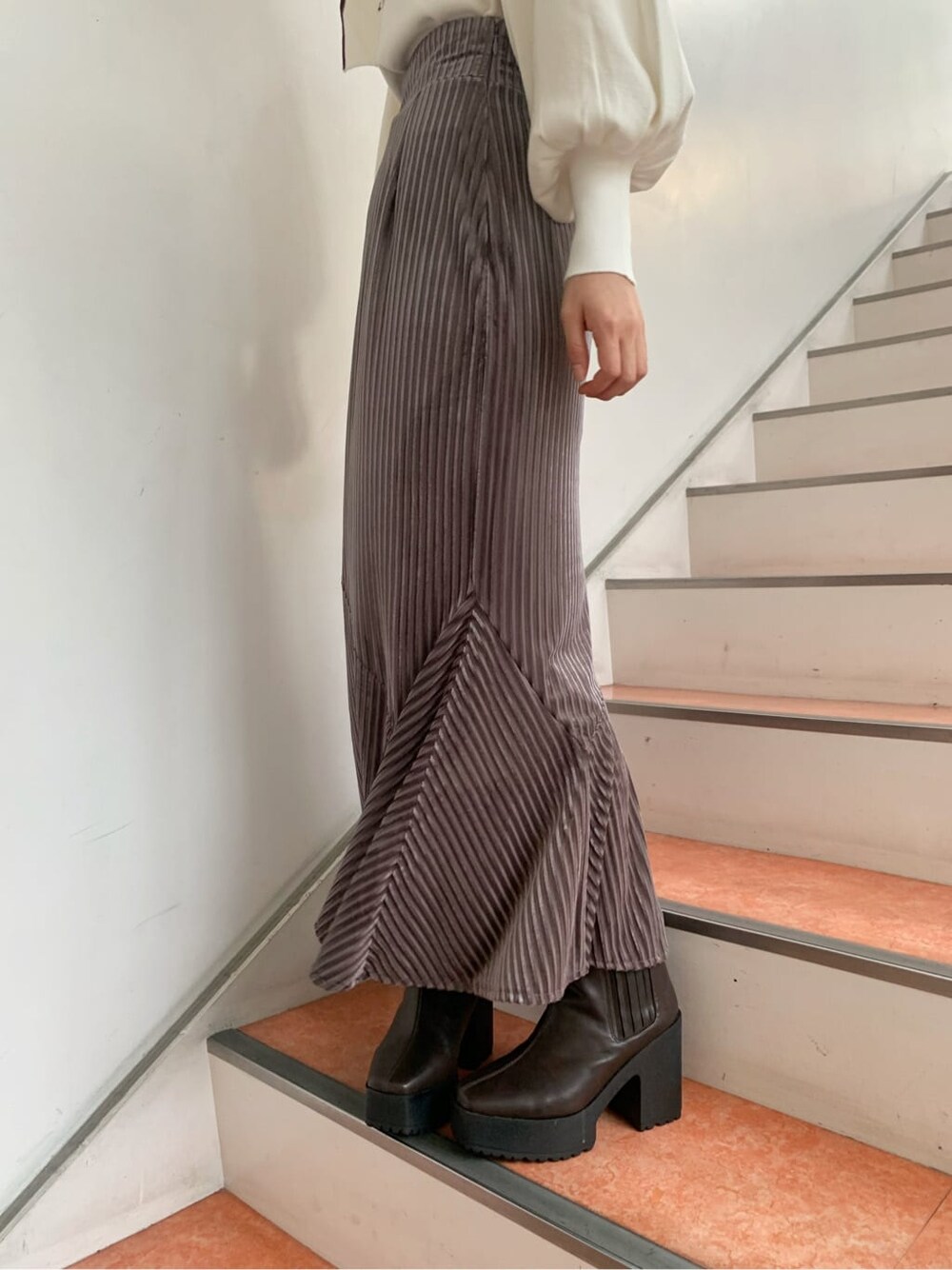 ホワイト系のニット/セーター、ブラウン系のブーツ、ベージュ系のスカートを着用したレディースの秋コーディネートの7枚目の写真