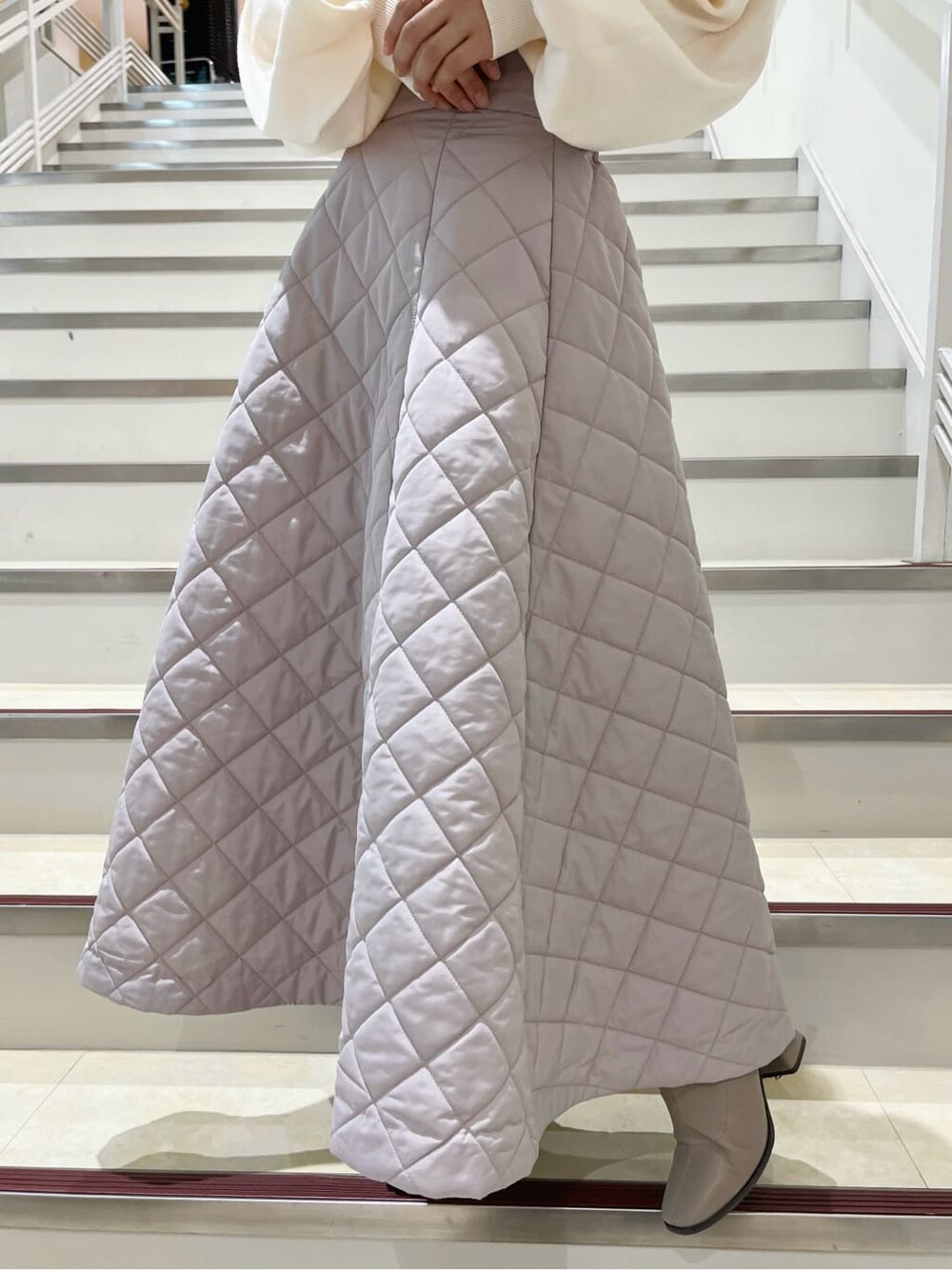 ホワイト系のニット/セーター、ピンク系のスカート、ベージュ系のブーツを着用したレディースの秋コーディネートの8枚目の写真