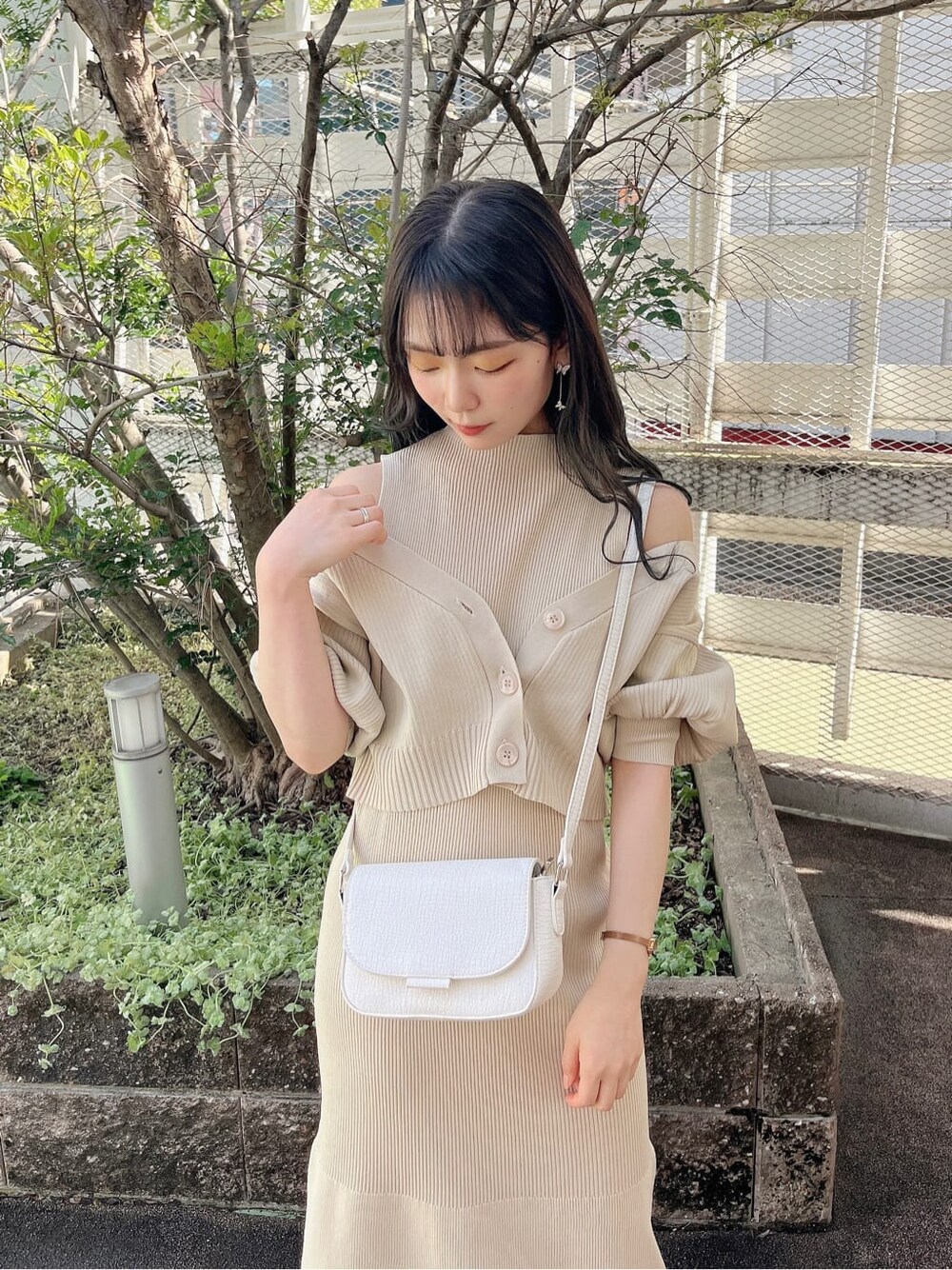 ホワイト系のパンプス、ホワイト系のショルダーバッグ、ベージュ系のワンピースを着用したレディースの春コーディネートの5枚目の写真