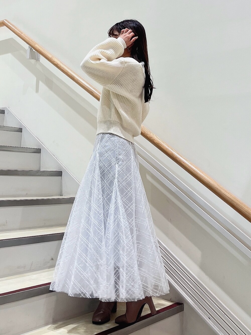 ホワイト系のニット/セーター、グレー系のスカート、ベージュ系のブーツを着用したレディースの冬コーディネートの5枚目の写真