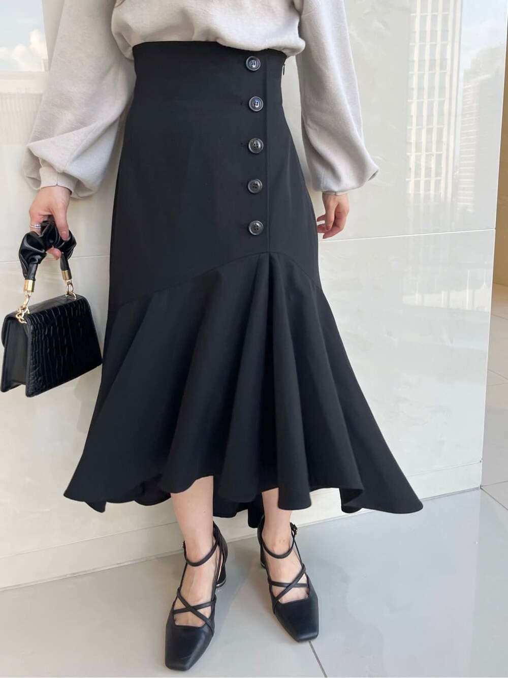 グレー系のニット/セーター、ブラック系のスカート、ブラック系のパンプスを着用したレディースの夏コーディネートの9枚目の写真