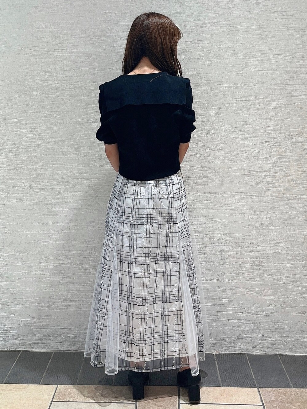 ブラック系のニット/セーター、ホワイト系のスカート、ブラック系のローファーを着用したレディースの夏コーディネートの4枚目の写真