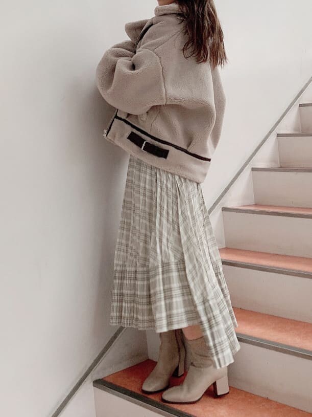 グリーン系のスカート、ホワイト系のニット/セーター、ベージュ系のブルゾンを着用したレディースの秋コーディネートの2枚目の写真