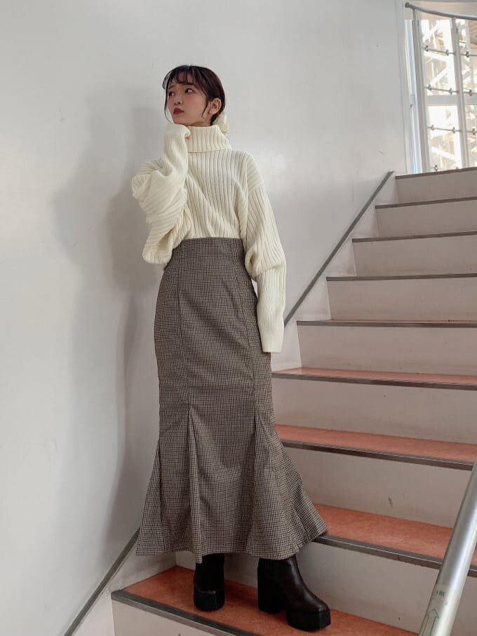 ブラウン系のブーツ、ブラウン系のスカート、ホワイト系のニット/セーターを着用したレディースの秋コーディネートの2枚目の写真