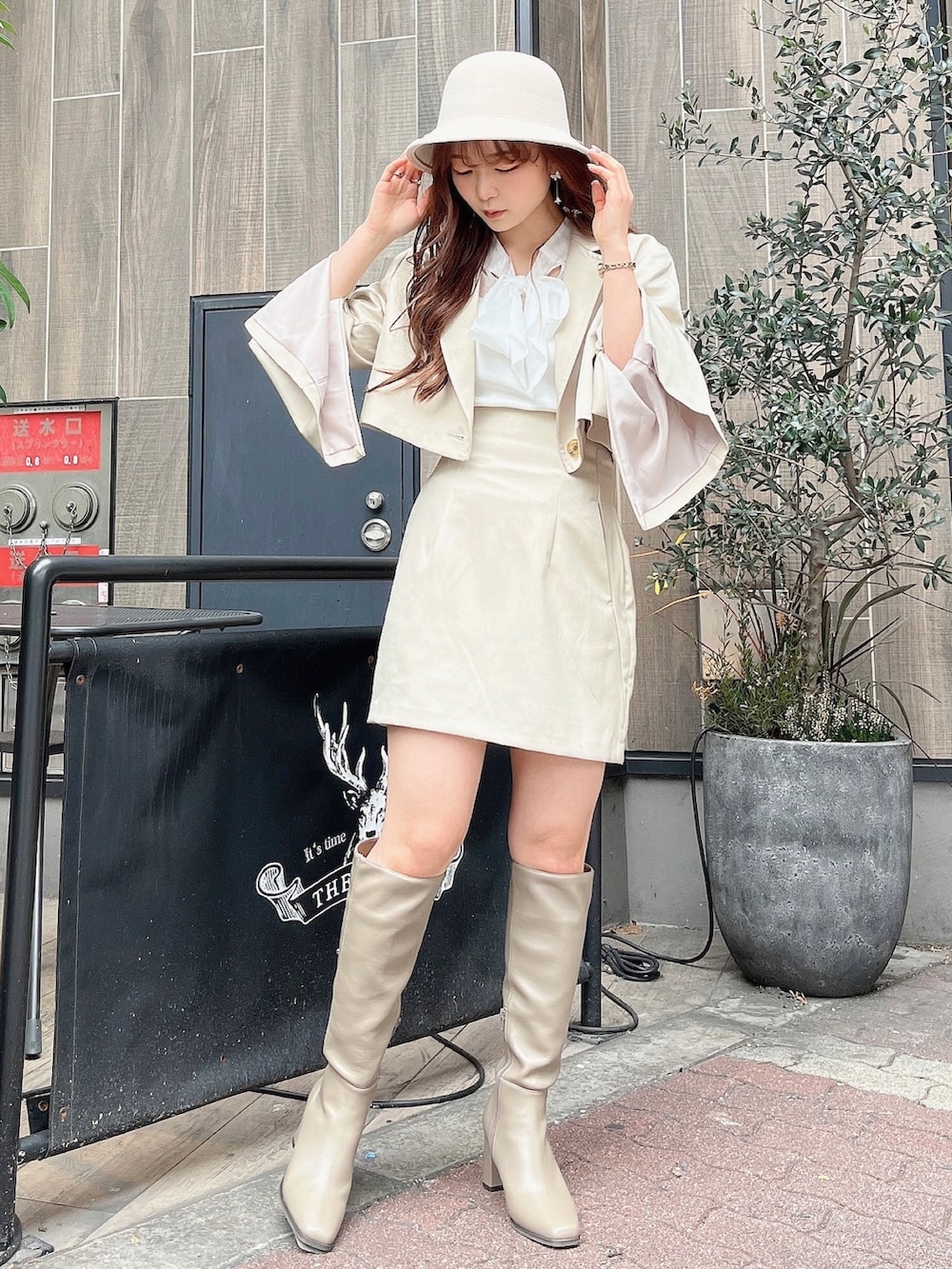 ベージュ系のテーラードジャケット、ホワイト系のニット/セーター、ベージュ系のスカートを着用したレディースの冬コーディネートの3枚目の写真