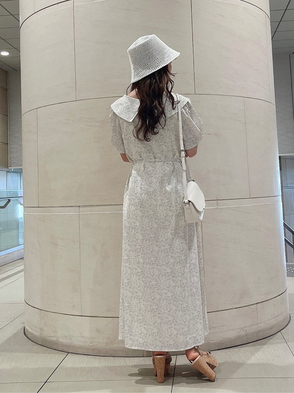 ベージュ系のサンダル、ホワイト系のワンピース、ホワイト系のハットを着用したレディースの春コーディネートの3枚目の写真