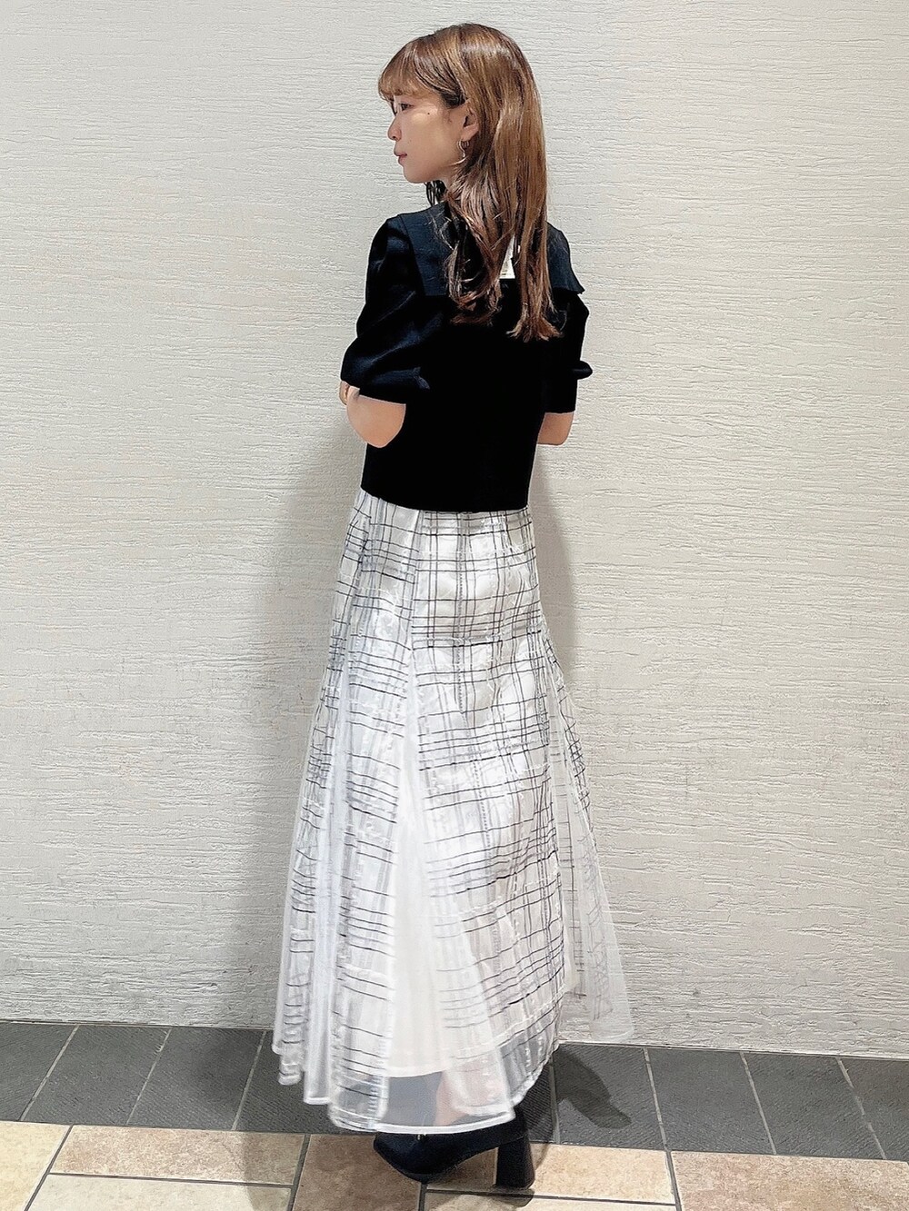 ブラック系のニット/セーター、ホワイト系のスカート、ブラック系のローファーを着用したレディースの夏コーディネートの2枚目の写真