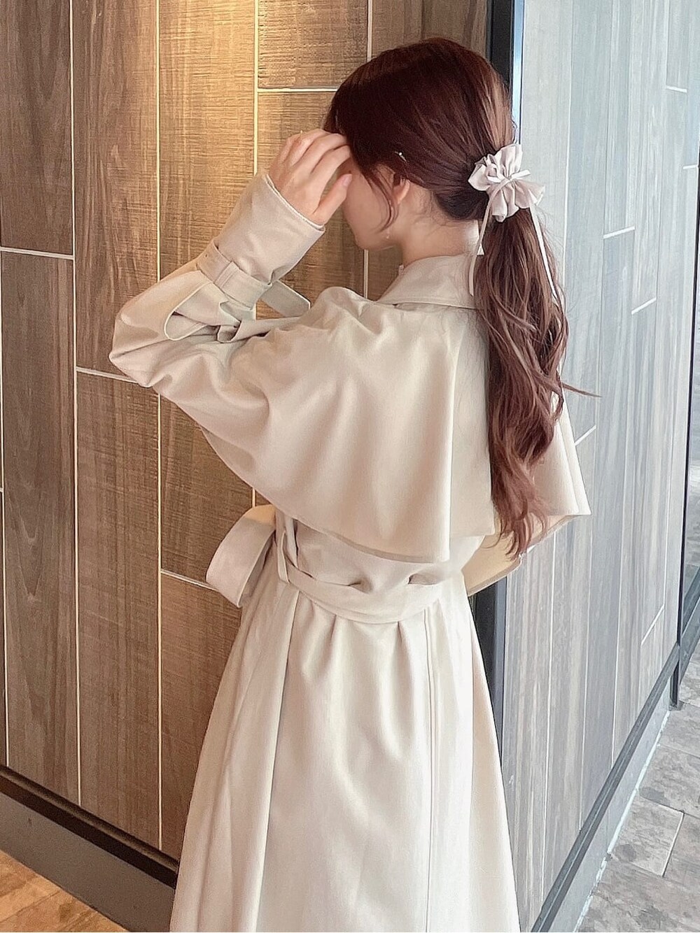 ベージュ系のトレンチコート、ベージュ系のブーツ、ベージュ系のスカートを着用したレディースの秋コーディネートの7枚目の写真