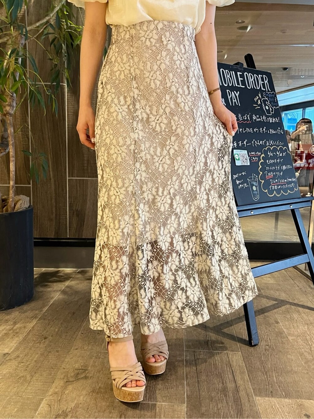 ベージュ系のスカート、ベージュ系のサンダル、イエロー系のシャツ/ブラウスを着用したレディースの夏コーディネートの8枚目の写真