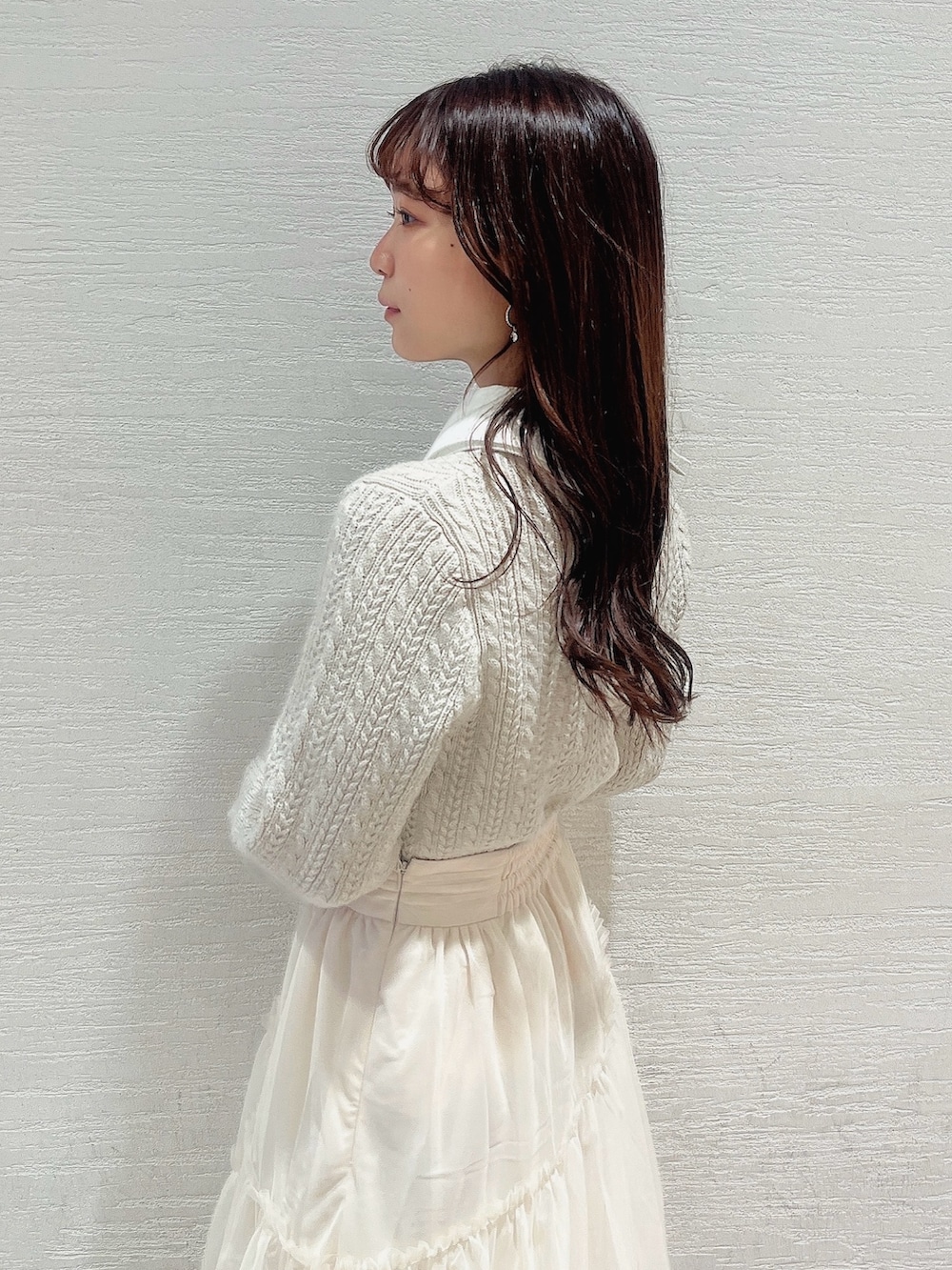 ベージュ系のニット/セーター、ホワイト系のスカート、ベージュ系のブーツを着用したレディースの冬コーディネートの6枚目の写真