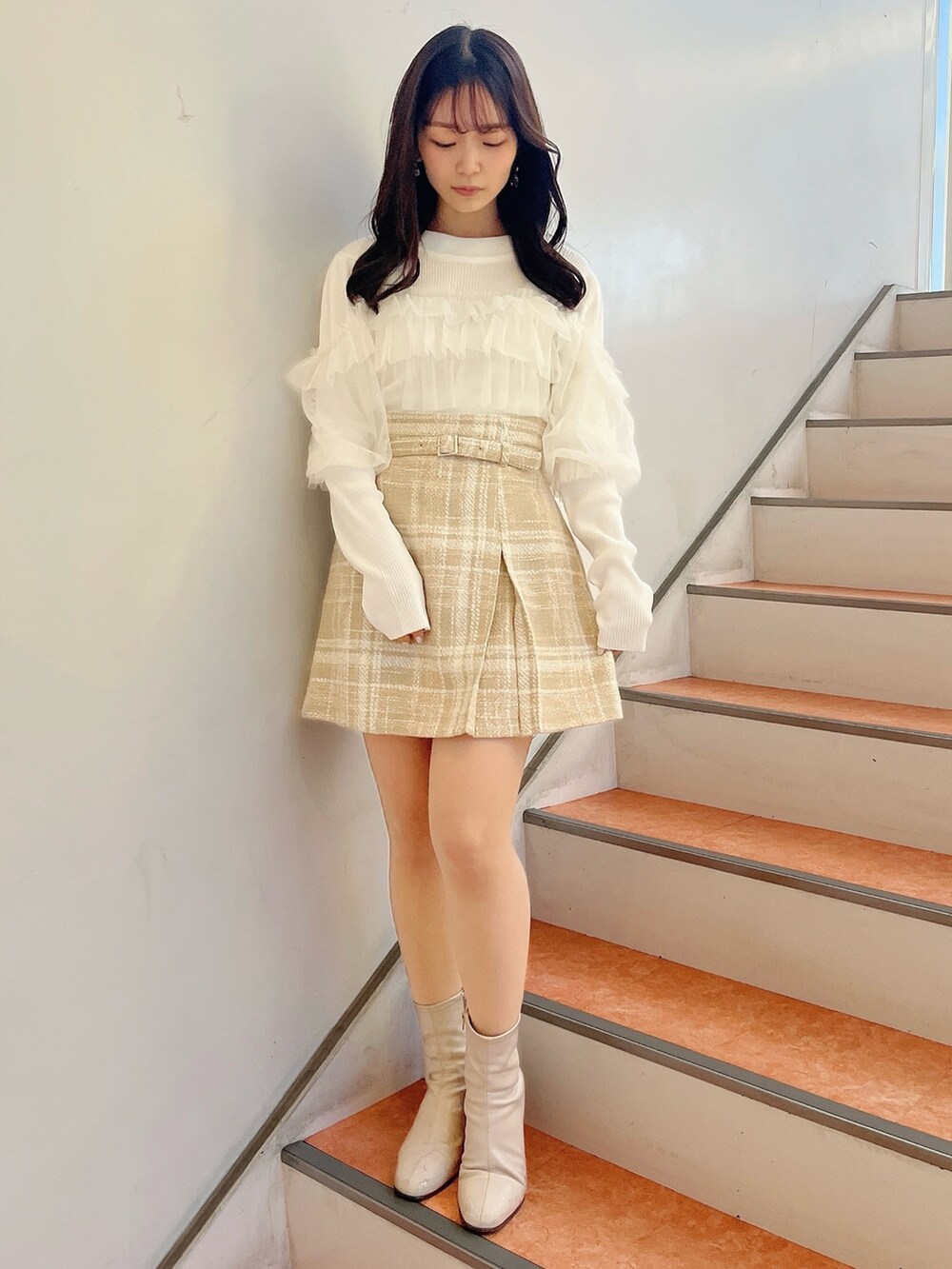 ホワイト系のニット/セーター、ベージュ系のスカート、ベージュ系のブーツを着用したレディースの冬コーディネートの3枚目の写真