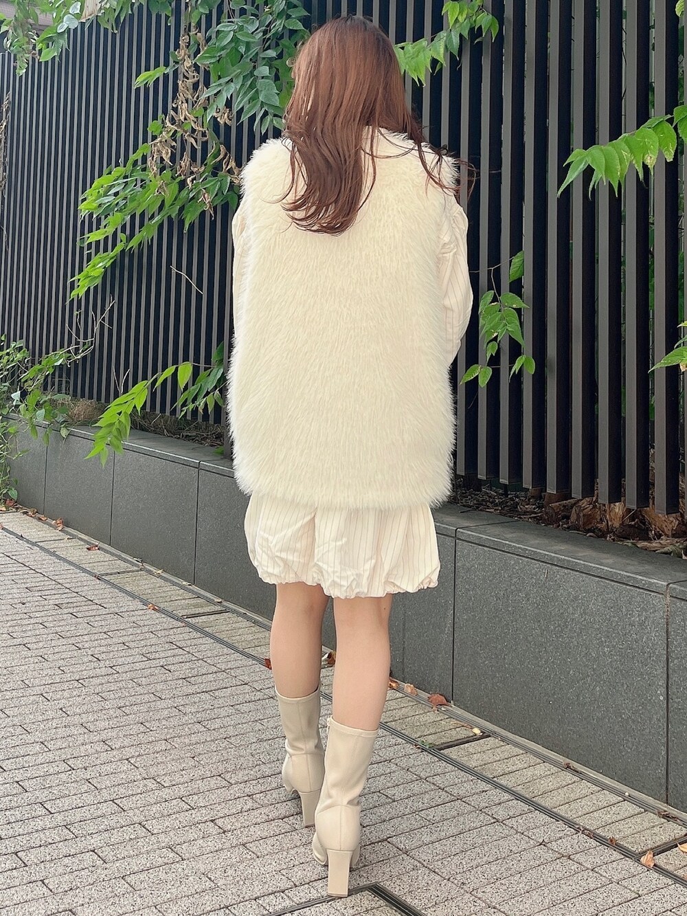 ホワイト系のベスト、ベージュ系のワンピース、ホワイト系のブーツを着用したレディースの秋コーディネートの2枚目の写真