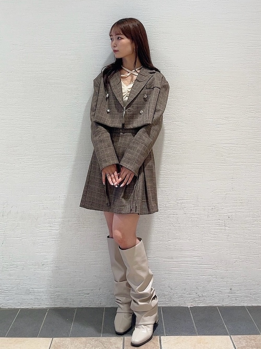 ベージュ系のブーツ、ブラウン系のスカート、ホワイト系のニット/セーターを着用したレディースの秋コーディネートの2枚目の写真