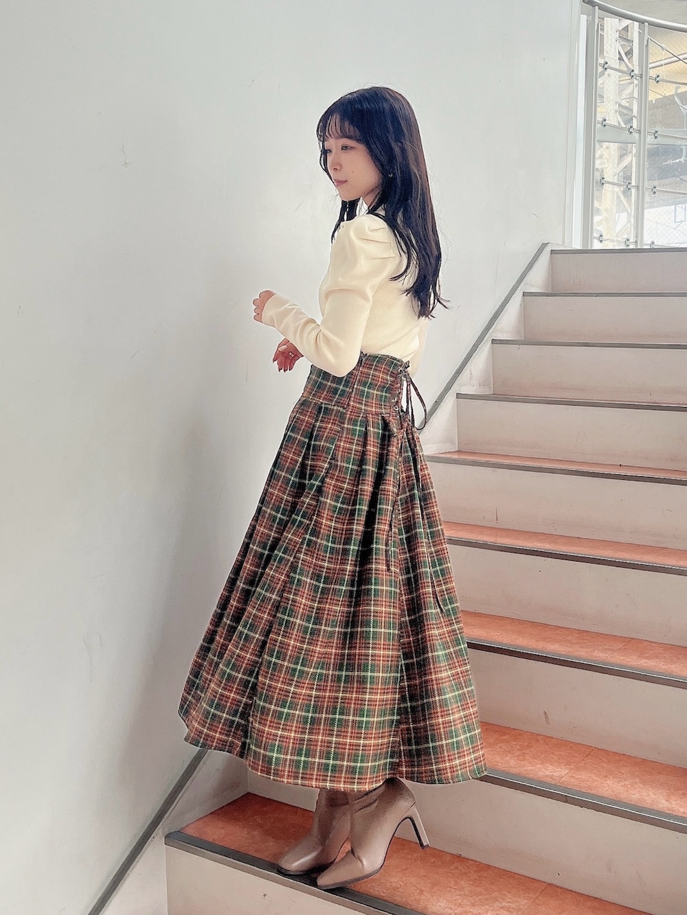 ホワイト系のニット/セーター、グリーン系のスカート、ベージュ系のブーツを着用したレディースの秋コーディネートの3枚目の写真