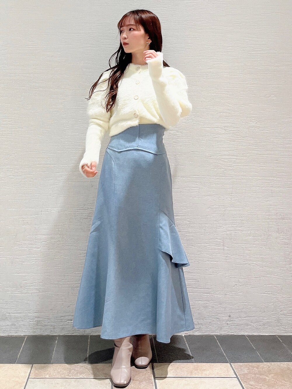ホワイト系のニット/セーター、ブルー系のスカート、ベージュ系のブーツを着用したレディースの冬コーディネートの3枚目の写真