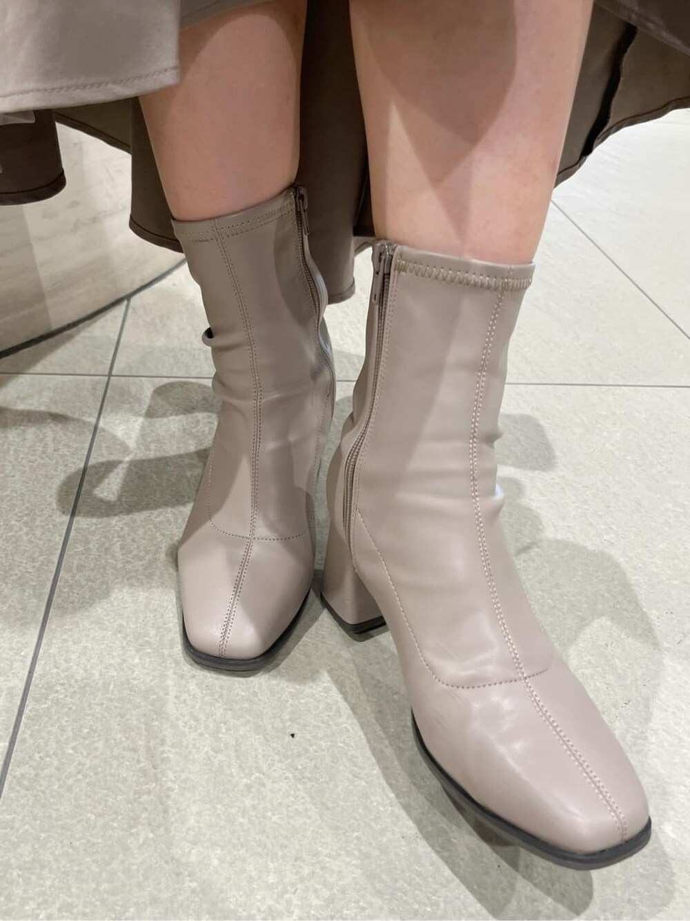 ベージュ系のブーツ、ベージュ系のスカート、ホワイト系のシャツ/ブラウスを着用したレディースの秋コーディネートの10枚目の写真