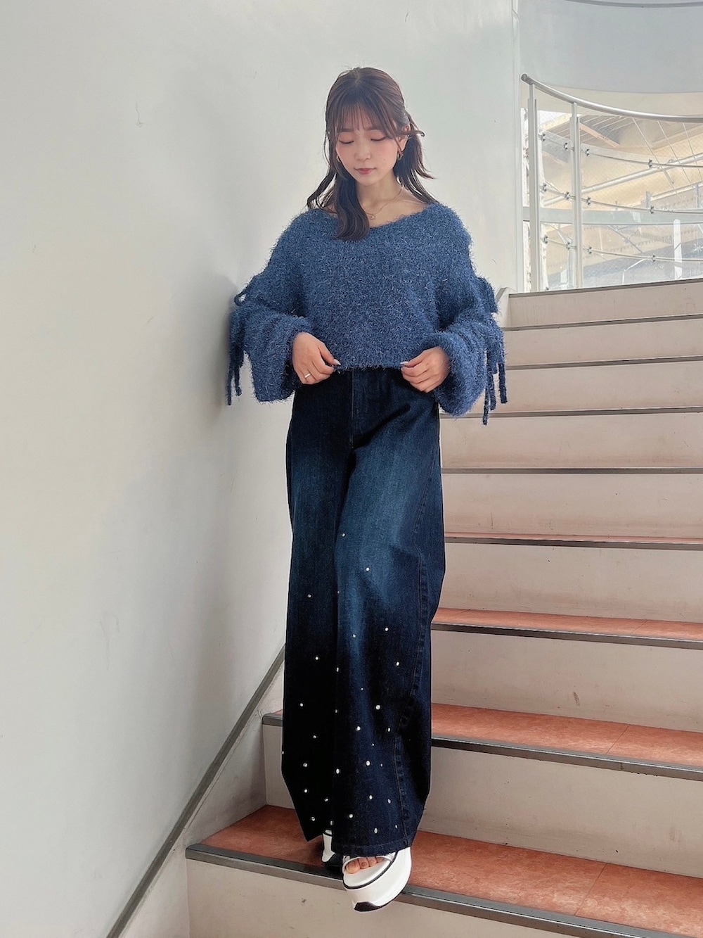 ブルー系のニット/セーター、ブルー系のデニムパンツ、ホワイト系のサンダルを着用したレディースの夏コーディネートの2枚目の写真