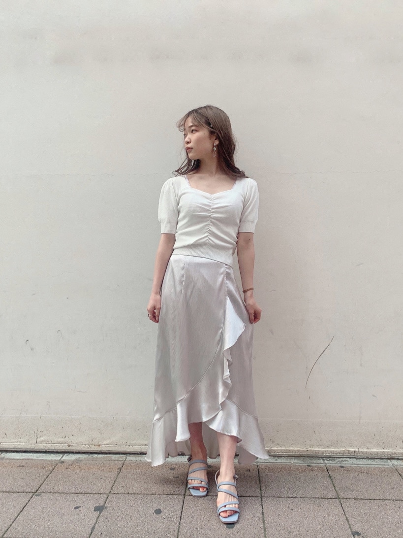 グレー系のスカート、ブルー系のサンダル、ホワイト系のニット/セーターを着用したレディースの春コーディネートの4枚目の写真