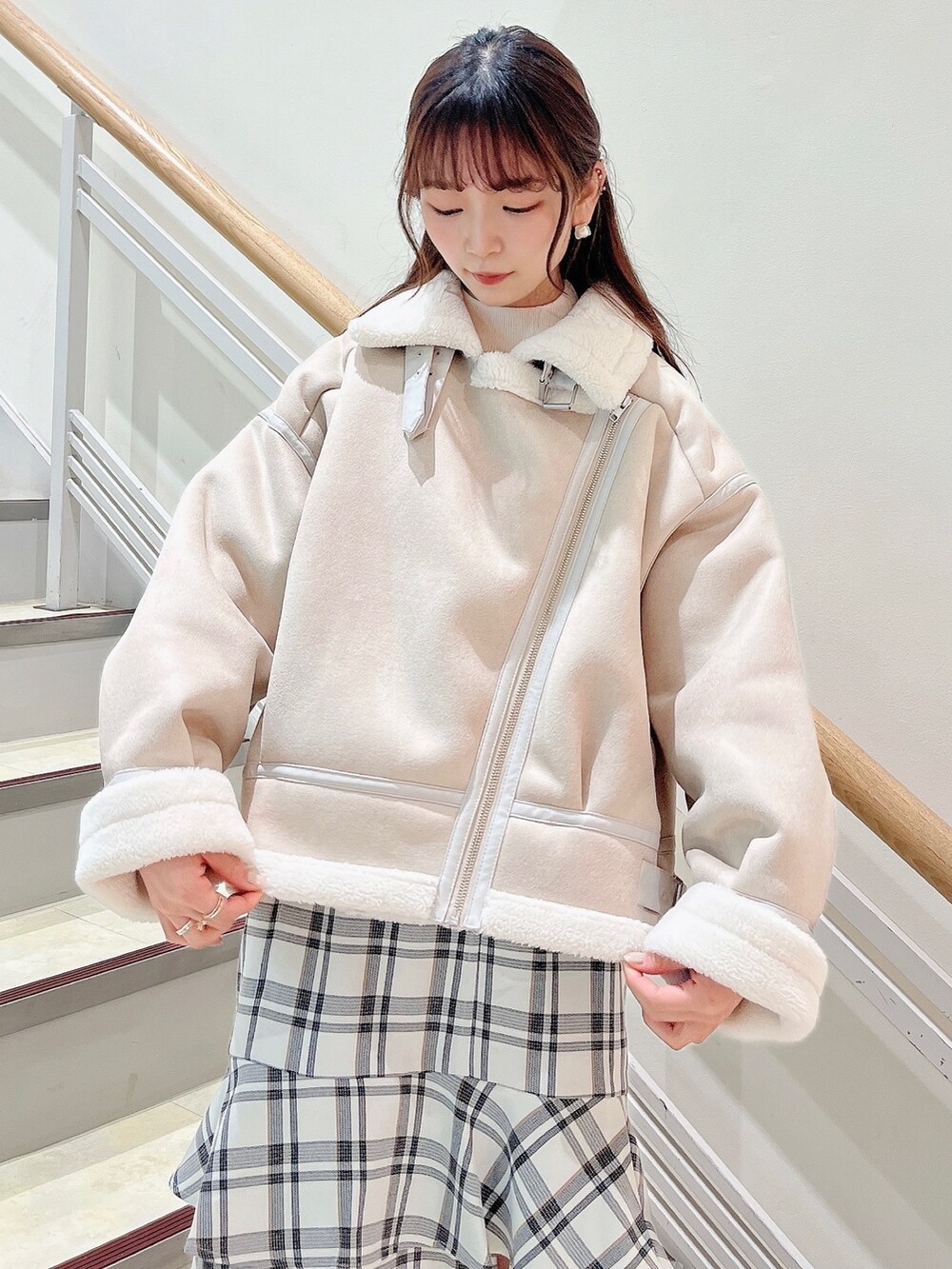 ホワイト系のブルゾン、ホワイト系のスカート、ベージュ系のブーツを着用したレディースの冬コーディネートの8枚目の写真