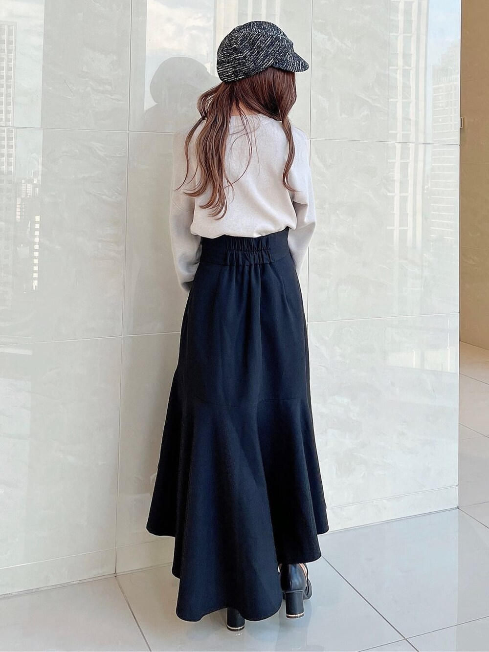 グレー系のニット/セーター、ブラック系のスカート、ブラック系のパンプスを着用したレディースの夏コーディネートの4枚目の写真