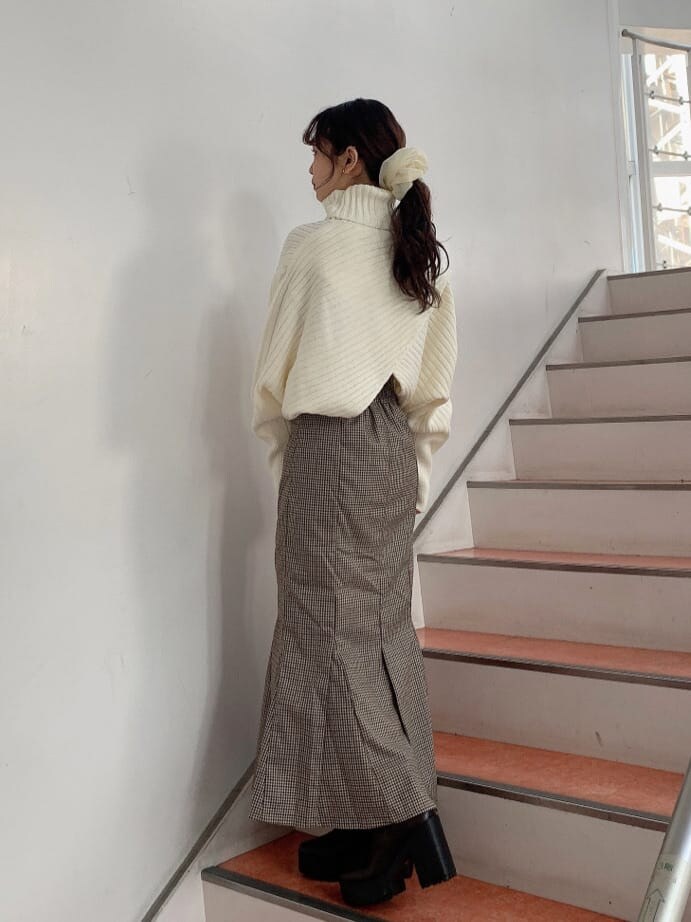 ブラウン系のブーツ、ブラウン系のスカート、ホワイト系のニット/セーターを着用したレディースの秋コーディネートの3枚目の写真