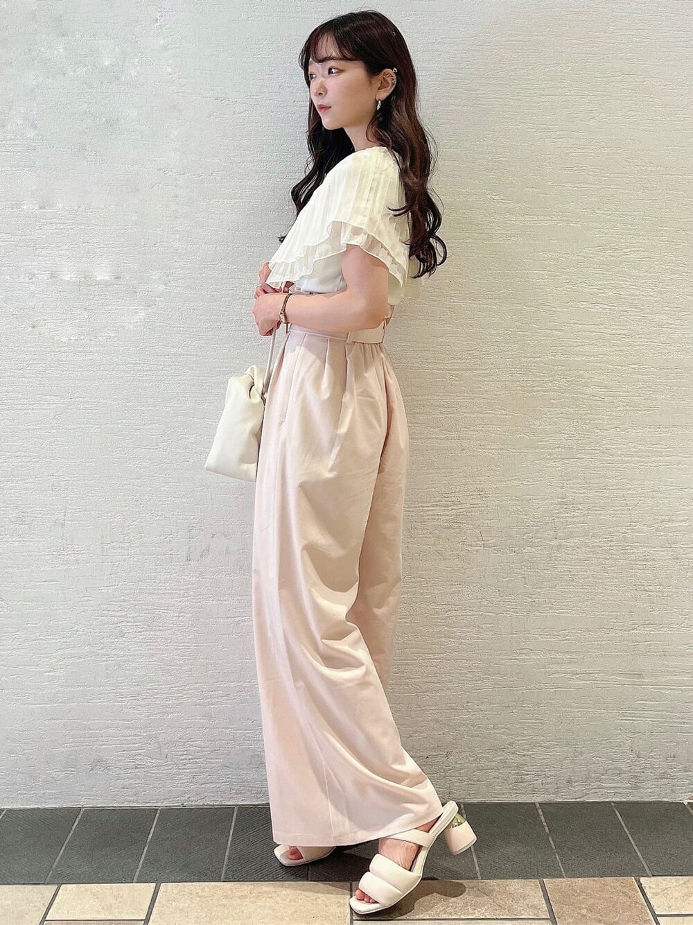 ベージュ系のその他パンツ、ホワイト系のサンダル、ホワイト系のニット/セーターを着用したレディースの夏コーディネートの2枚目の写真