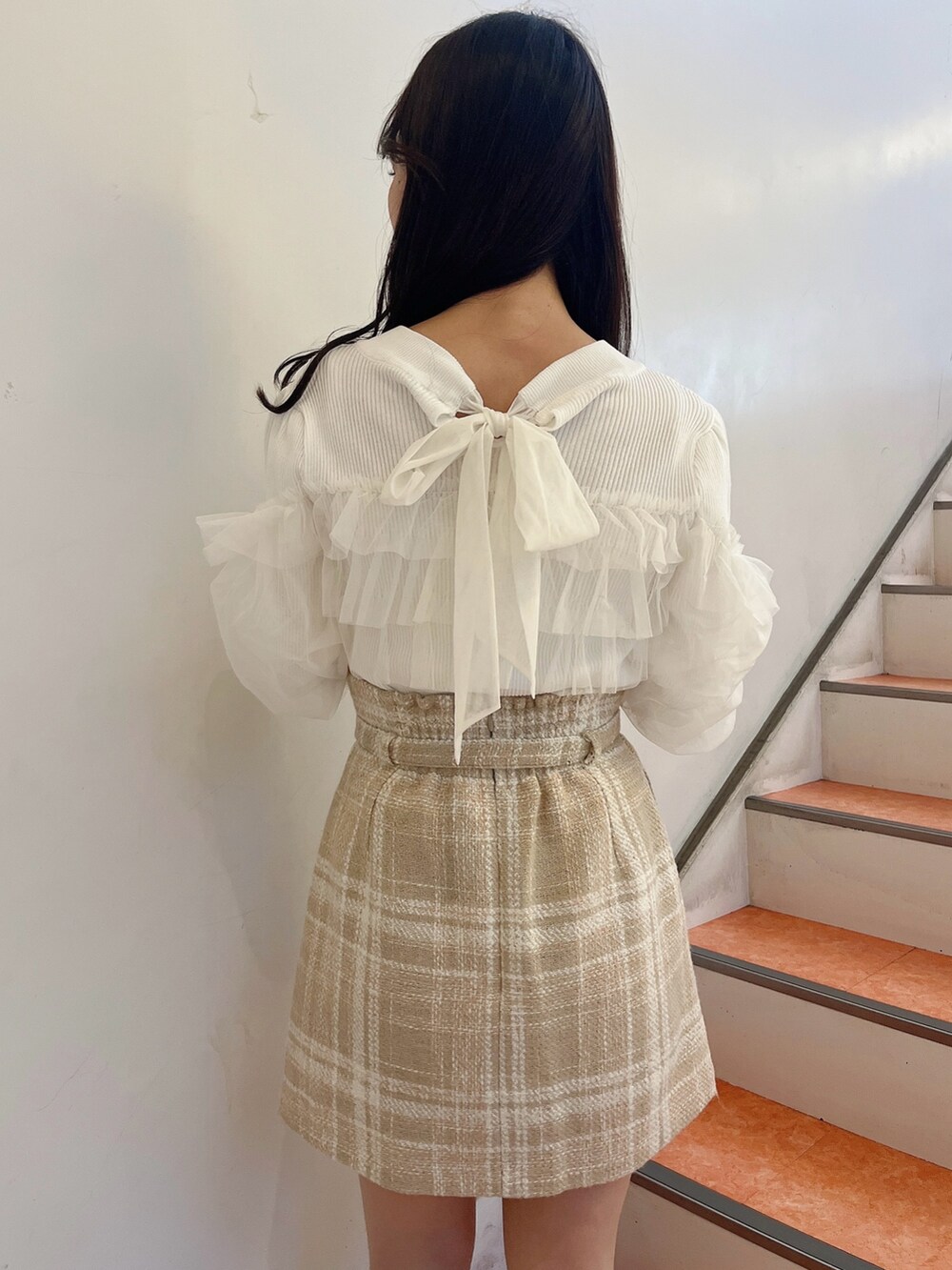 ホワイト系のニット/セーター、ベージュ系のスカート、ベージュ系のブーツを着用したレディースの冬コーディネートの8枚目の写真