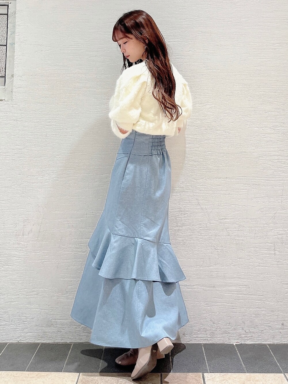 ホワイト系のニット/セーター、ブルー系のスカート、ベージュ系のブーツを着用したレディースの冬コーディネートの2枚目の写真