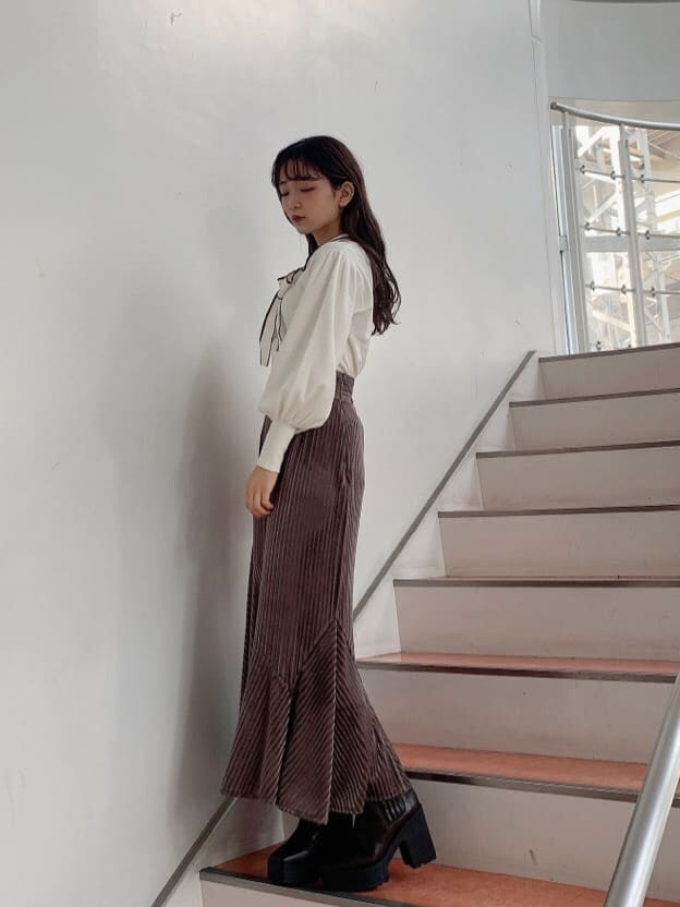 ホワイト系のニット/セーター、ブラウン系のブーツ、ベージュ系のスカートを着用したレディースの秋コーディネートの2枚目の写真