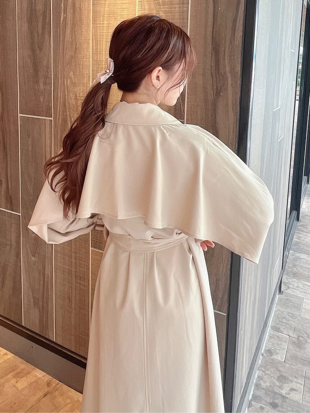 ベージュ系のトレンチコート、ベージュ系のブーツ、ベージュ系のスカートを着用したレディースの秋コーディネートの6枚目の写真