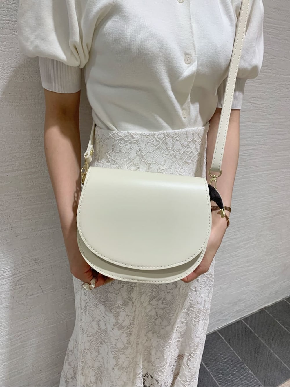 ホワイト系のスカート、ホワイト系のパンプス、ベージュ系のショルダーバッグを着用したレディースの夏コーディネートの10枚目の写真