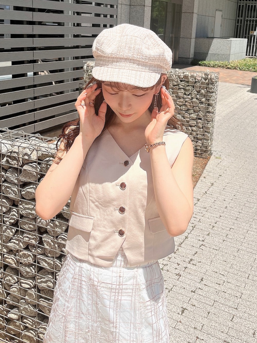 ベージュ系のベスト、ベージュ系のスカート、ホワイト系のローファーを着用したレディースの夏コーディネートの10枚目の写真